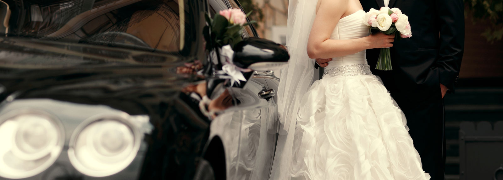 Wedding couple by luxury sedan