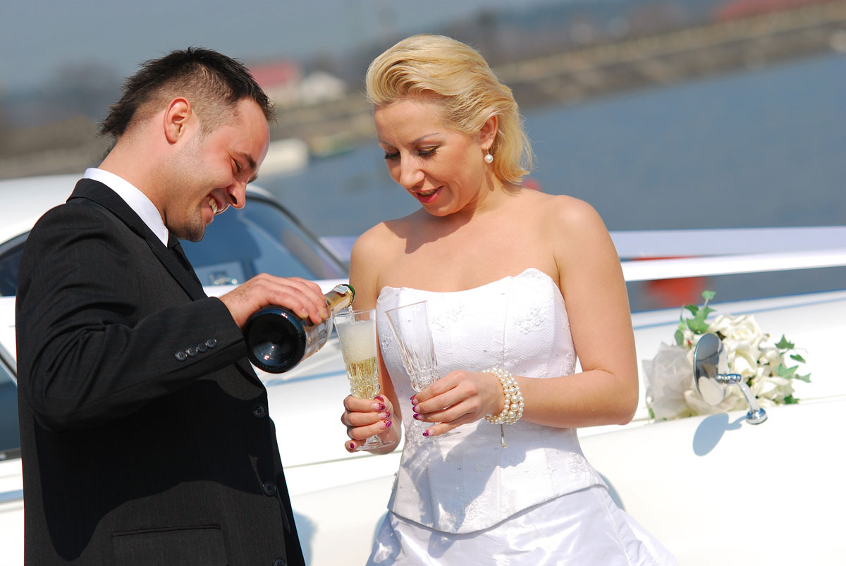 Wedding couple toasting by Rolls Royce